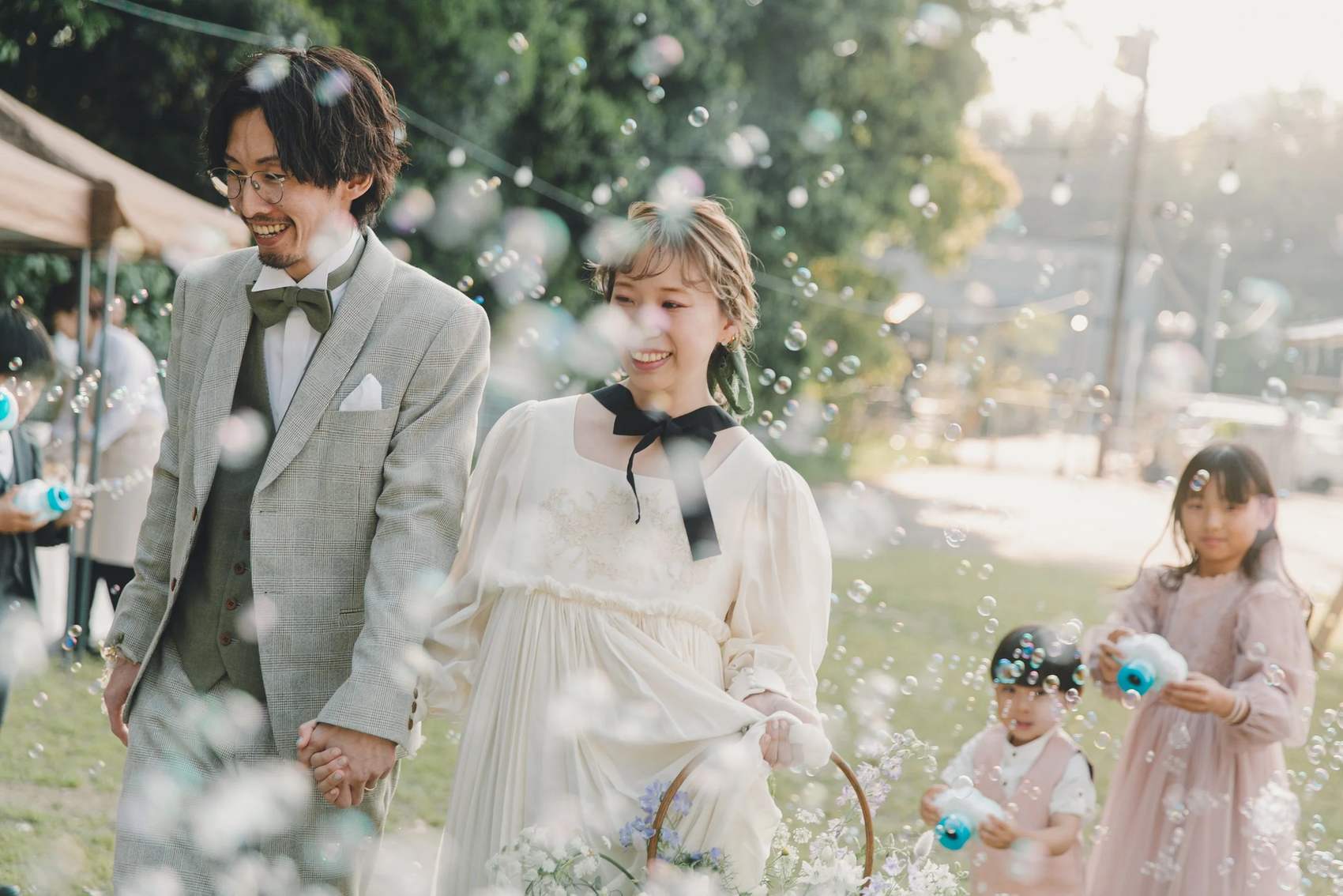 シャボン玉に包まれて歩く新郎新婦と子どもたち