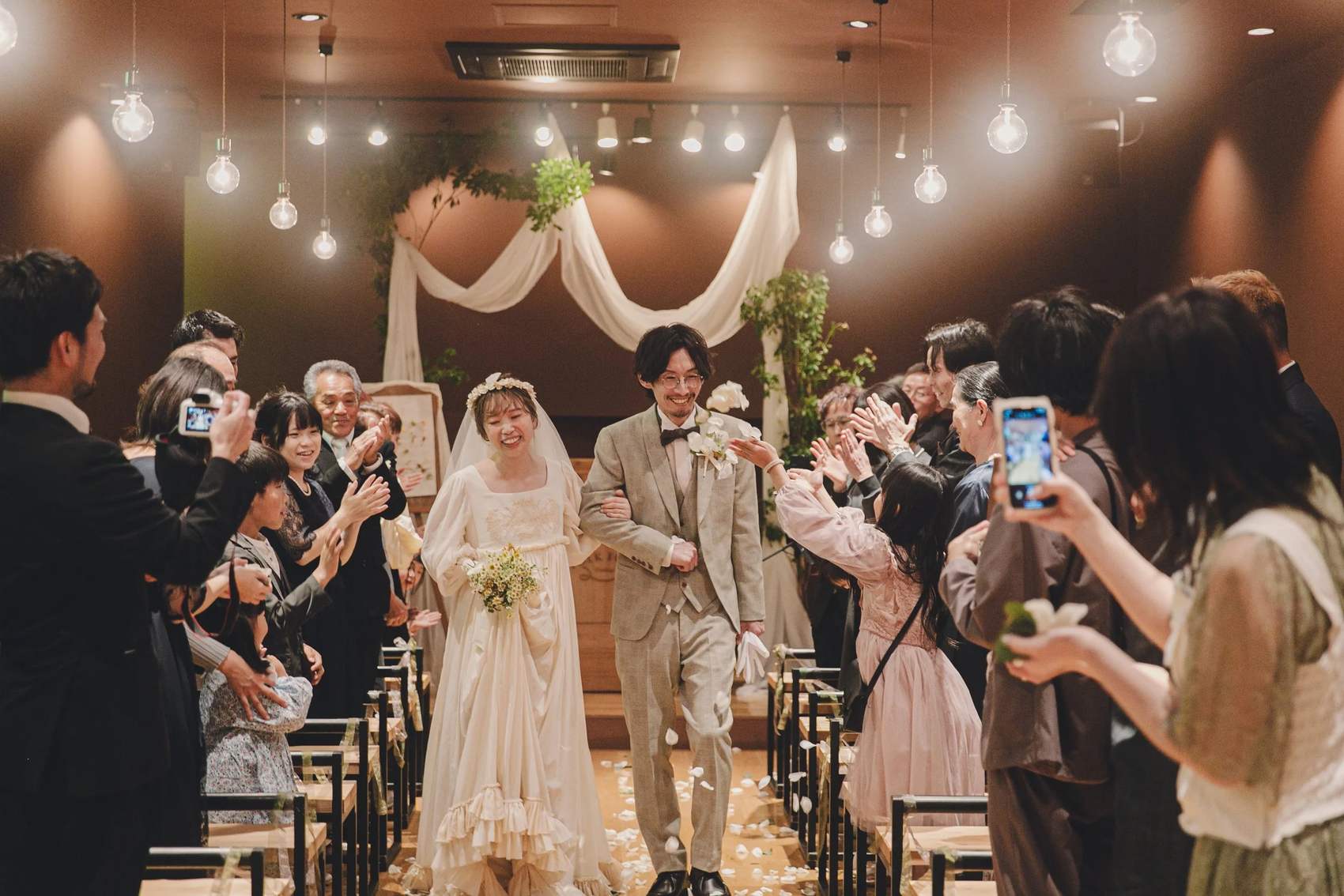 挙式会場でフラワーシャワーに包まれて退場する新郎新婦